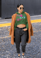 Green eco-friendly cropped hoodie with colorful design, styled with a brown coat for a trendy and sustainable women's outfit.