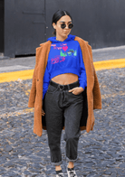 Blue cropped hoodie with vibrant eco-themed print, layered under a coat for a bold and sustainable women's streetwear look.