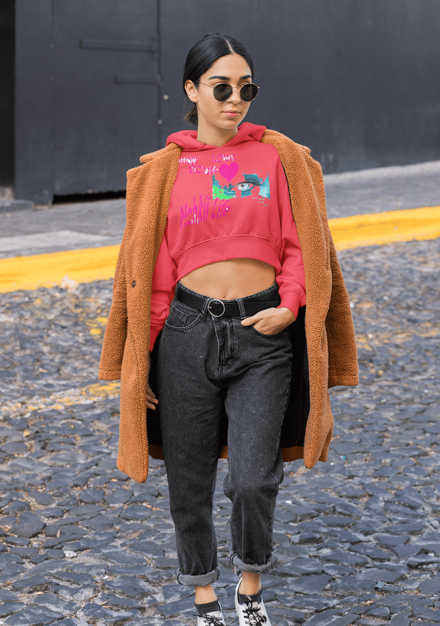 Red eco-friendly cropped hoodie with colorful graphic, styled with a brown coat for a bold sustainable women's activewear look.