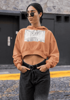 Cropped eco hoodie in peach tone for women, featuring bold front print, combining sustainable fashion with breathable comfort.