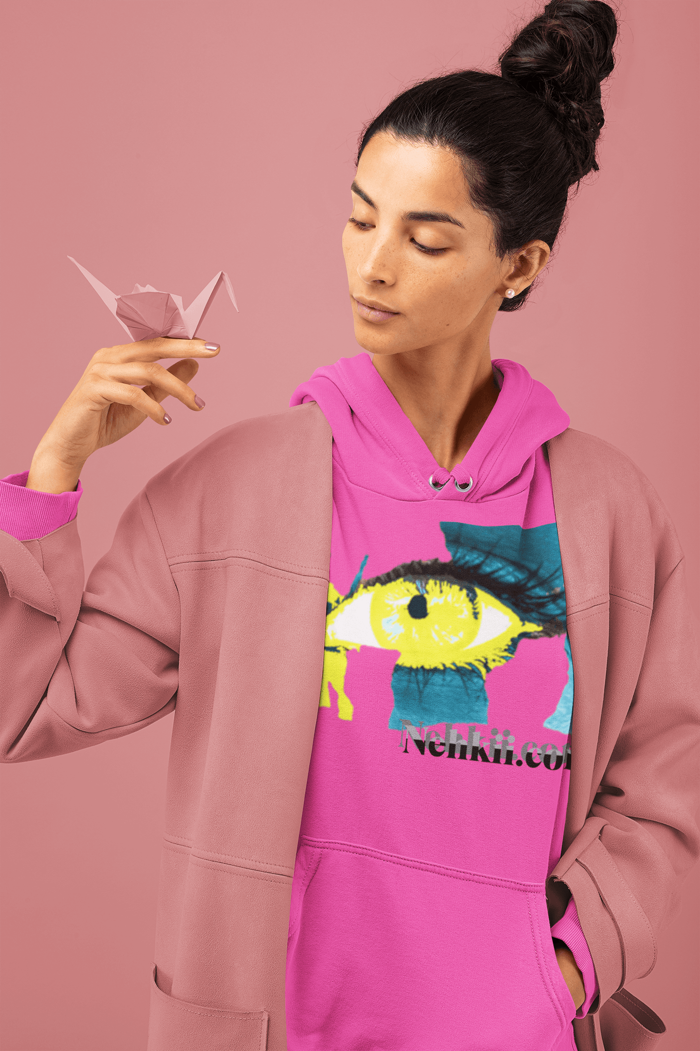 Pink cropped women's hoodie featuring a vibrant eye design and empowerment message, layered with a gray jacket. Sustainable and stylish activewear.