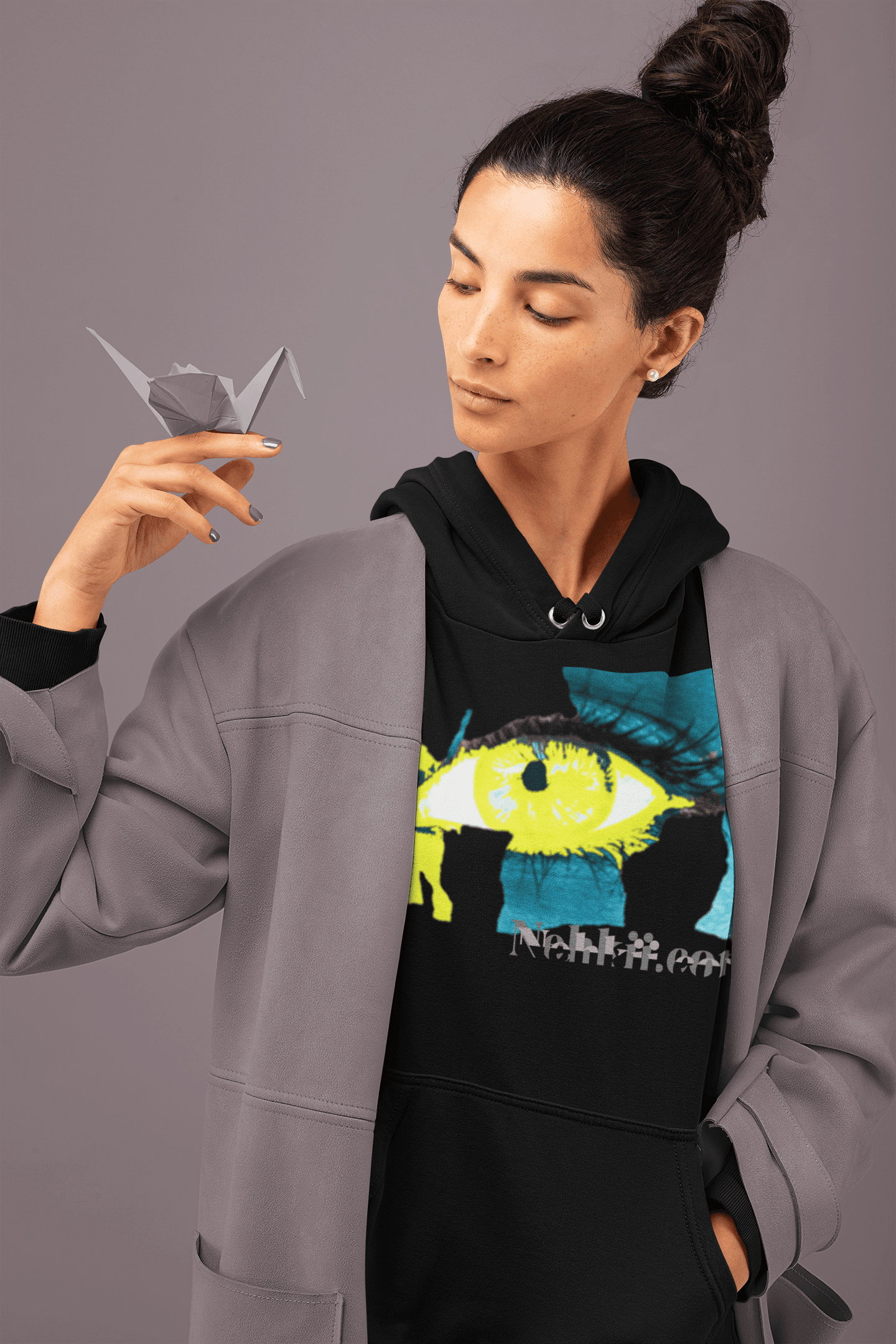 Cropped women's hoodie in black with bold eye graphic and empowerment text, styled under a gray coat. Eco-friendly activewear for modern women.